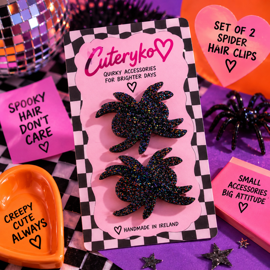 Set of two black glitter spider hair clips by Cuteryko on an orange background