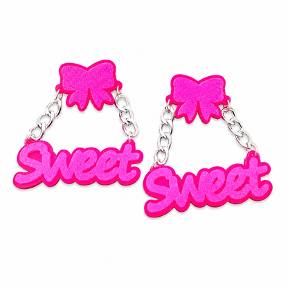 Oversized neon pink SWEET statement earrings with bow tops on white background