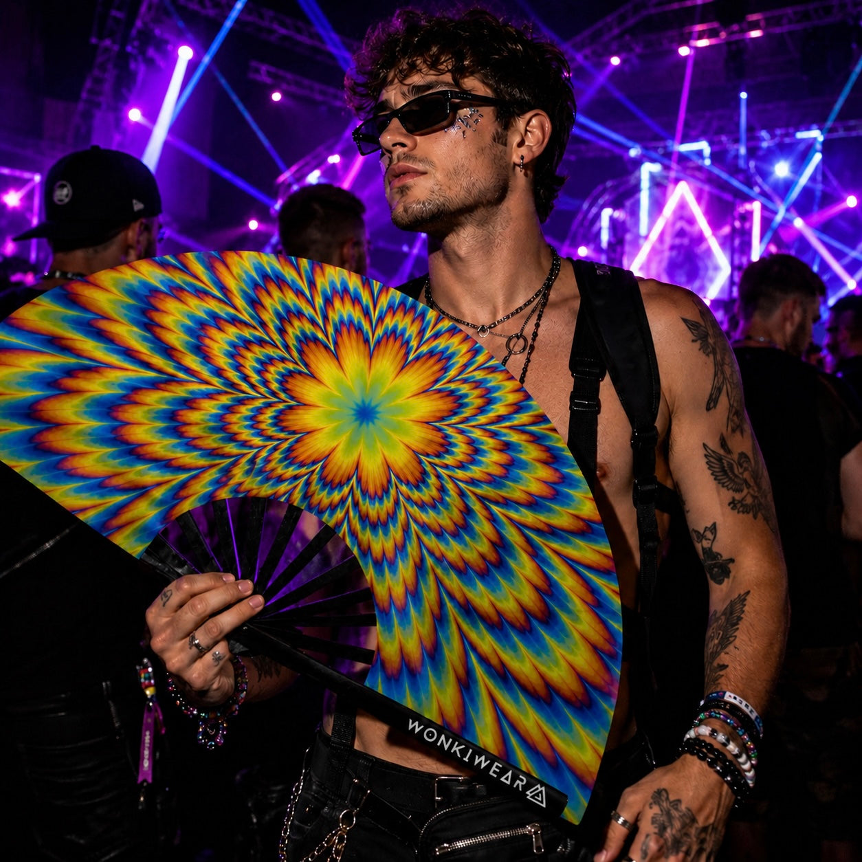 Male raver holding Tripping XL UV reactive festival fan inside nightclub rave