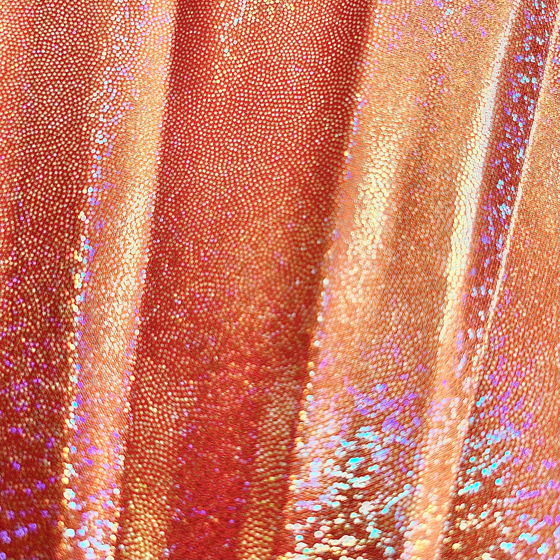 Close up of Venus Galaxy holographic metallic orange material showing fine rainbow reflective speckles