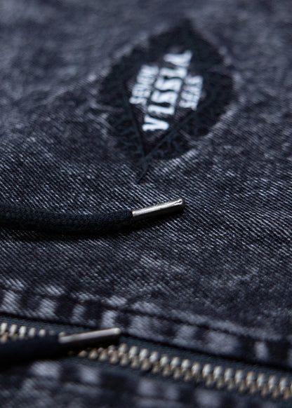 Close-up of the Vissla chest logo and metal zip on the black acid-wash Wasson jacket