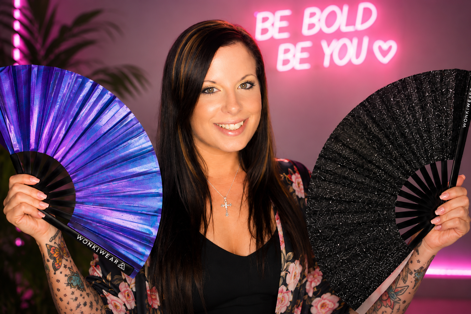 WonkiWear founder holding iridescent purple and black glitter XL festival fans in a bright branded studio portrait