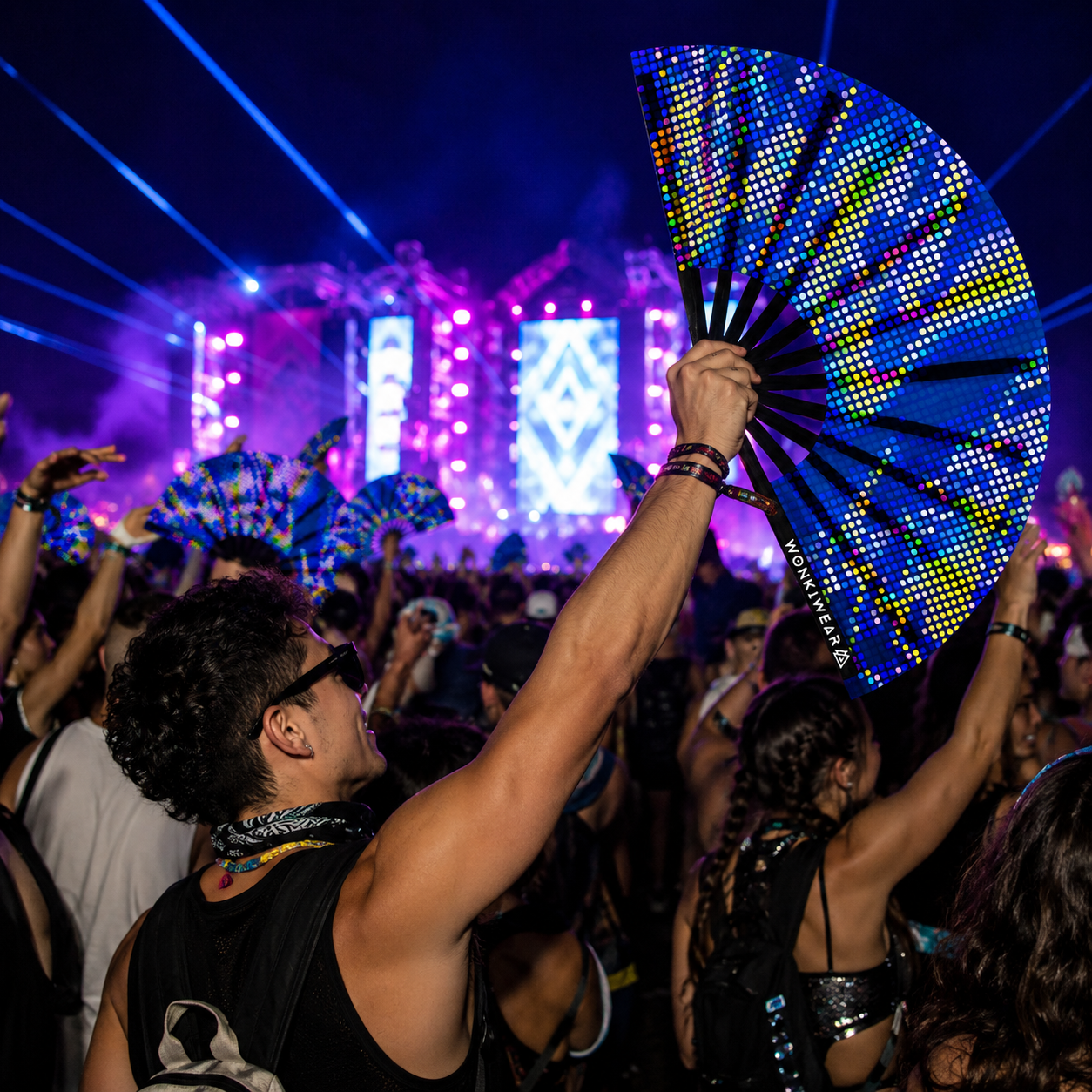 Crowd at music festival using UV reactive blue rave fans under blacklight