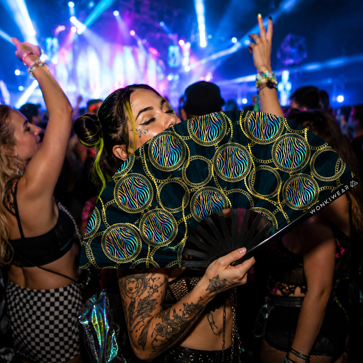 Festival crowd using XL UV reactive luxury rave fan at a nightclub or music festival