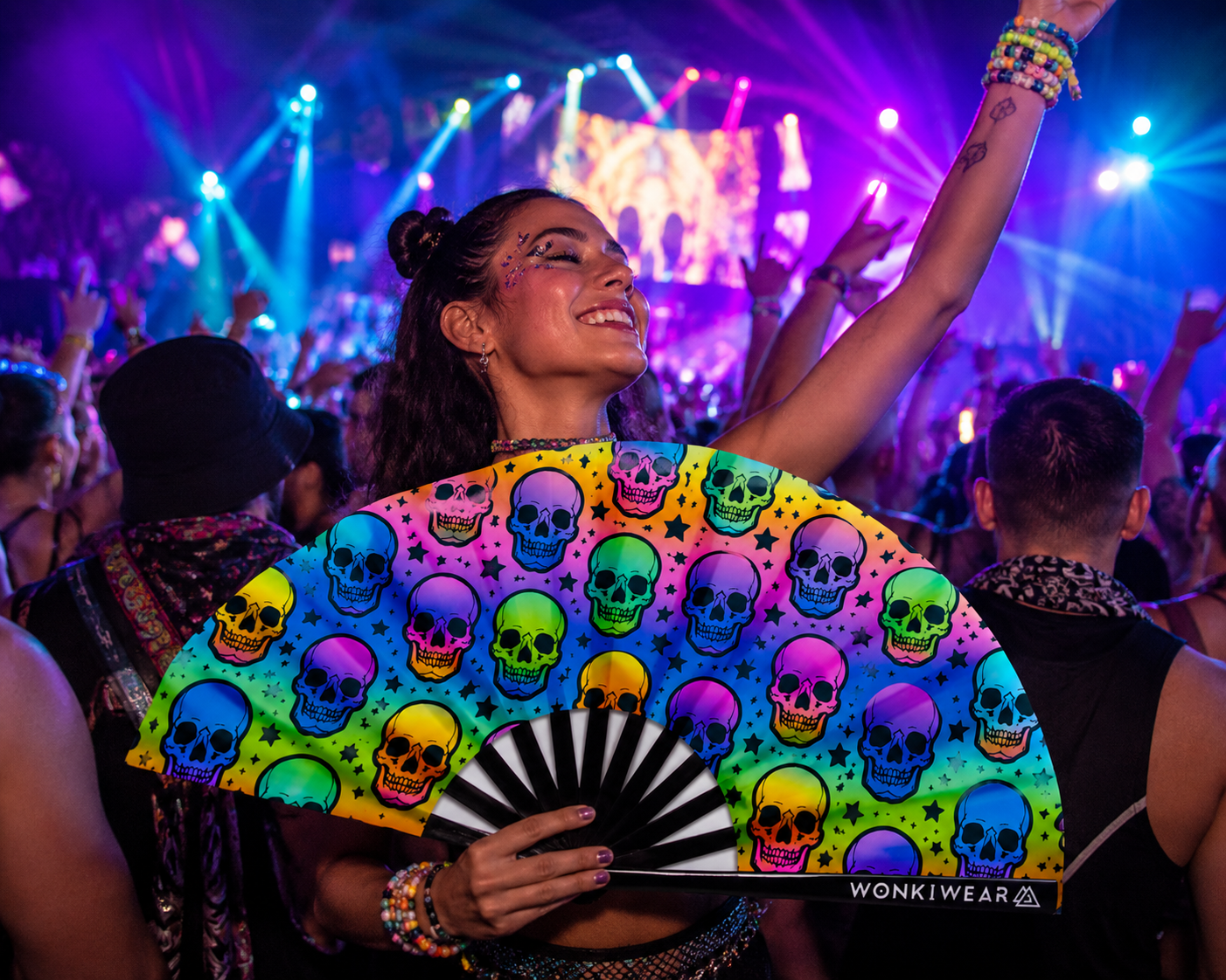 Festival crowd using XL UV reactive skull rave fan at nightclub or festival