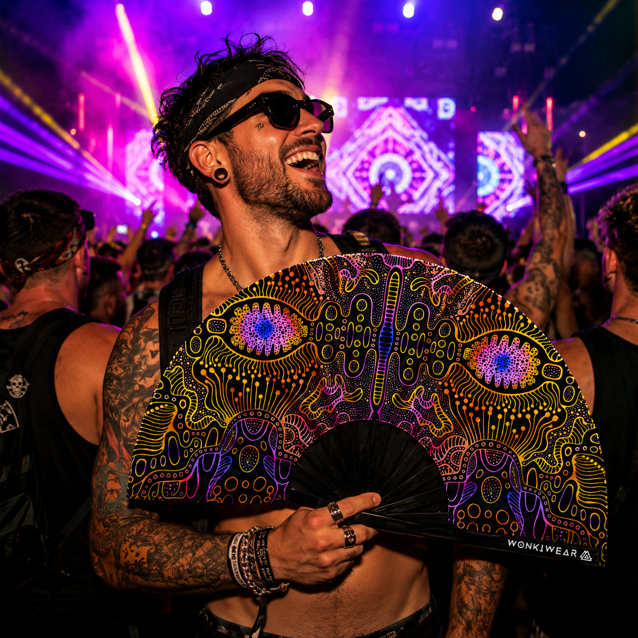 Festival crowd with UV reactive techno psytrance rave fan under neon event lighting