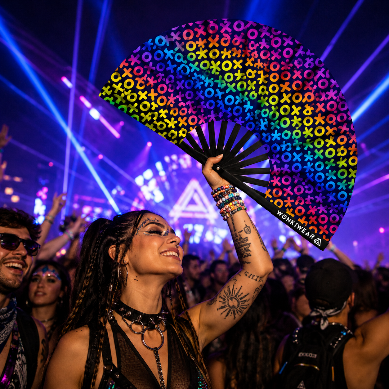 Crowd at music festival using neon UV reactive XOXO clack fans under blacklight lighting