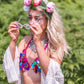 Woman wearing clear kaleidoscope glasses at a festival with boho outfit and face gems