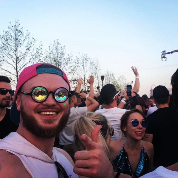 People wearing kaleidoscope glasses at a festival crowd with colourful reflections in lenses