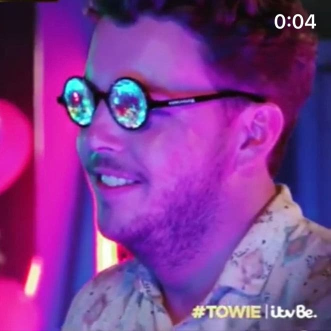 Towie man wearing kaleidoscope glasses under neon lights showing prism lens reflections