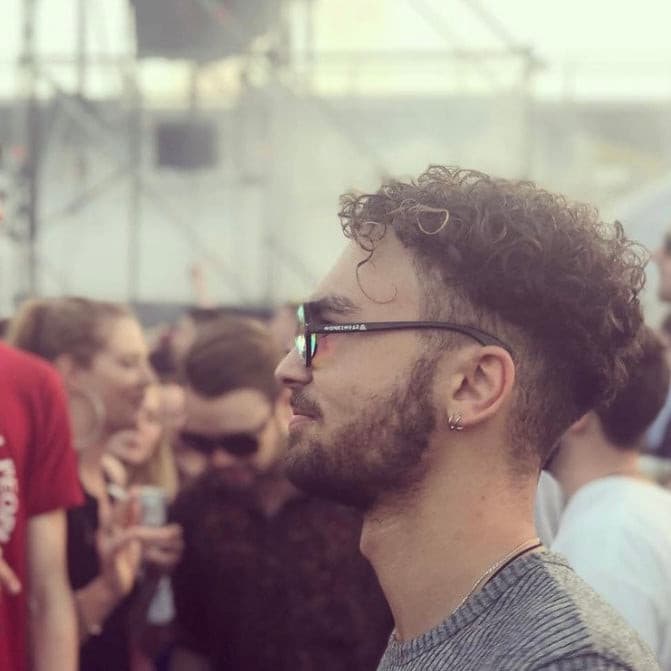 Man wearing kaleidoscope glasses at a festival in a crowded outdoor setting