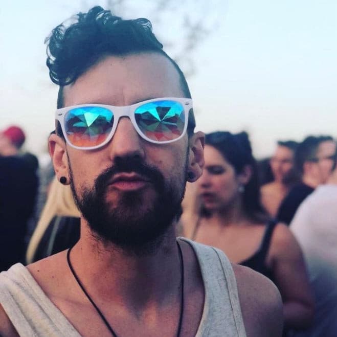 Man wearing wayfarer kaleidoscope glasses at a festival creating trippy prism light effects